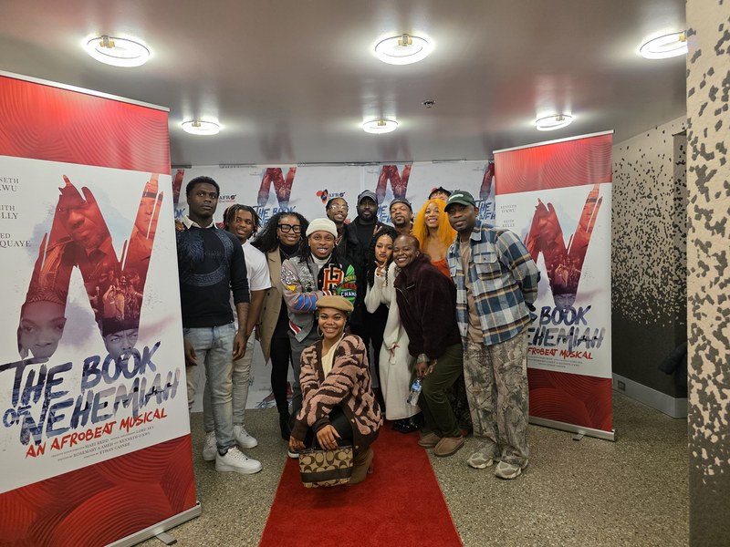 A large group posing between two Book of Nehemiah poster banners at the Chicago private screening